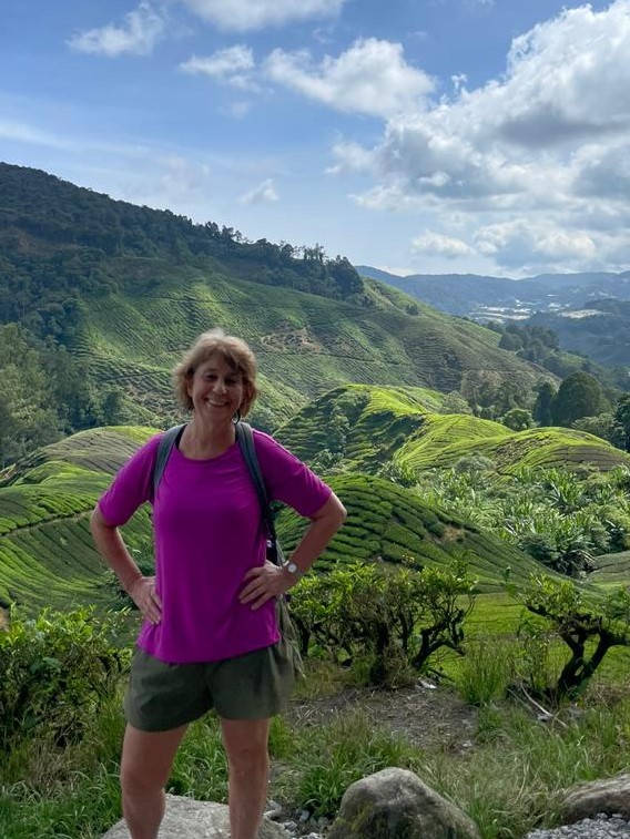 Jackie stands in front of a green mountain view in the Cameron Highlands, Malaysia