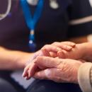 Image of an elderly person's hands being held by a health professional