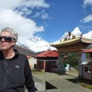 Jim Neilson, a white man with short white hair, stands in front of mountains and an ornate gate with sunglasses on
