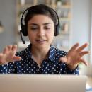Woman wearing a headset is talking to her laptop and gesturing with her hands