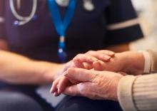 Image of an elderly person's hands being held by a health professional