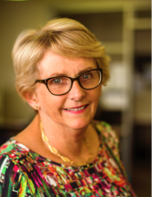 Cindy Farquhar, a white woman with blonde hair and glasses, looks at the camera and smiles