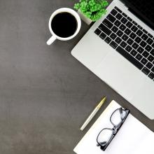 Image of a computer with a coffee cup, pen, and glasses