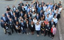 a large group of Cochrane Rehab members stare up at a drone camera and smile and wave