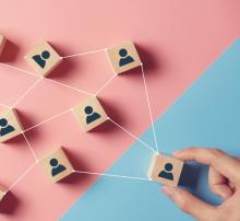 Image of wooden blocks with people avatars on them, connected by string and being pulled by a hand