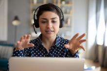 Woman wearing a headset is talking to her laptop and gesturing with her hands