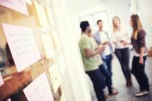 Group of people discussing in an office, with a brainstorming board in the foreground