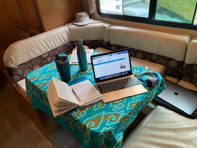picture of a table in a camper with a computer, a notebook sitting between them