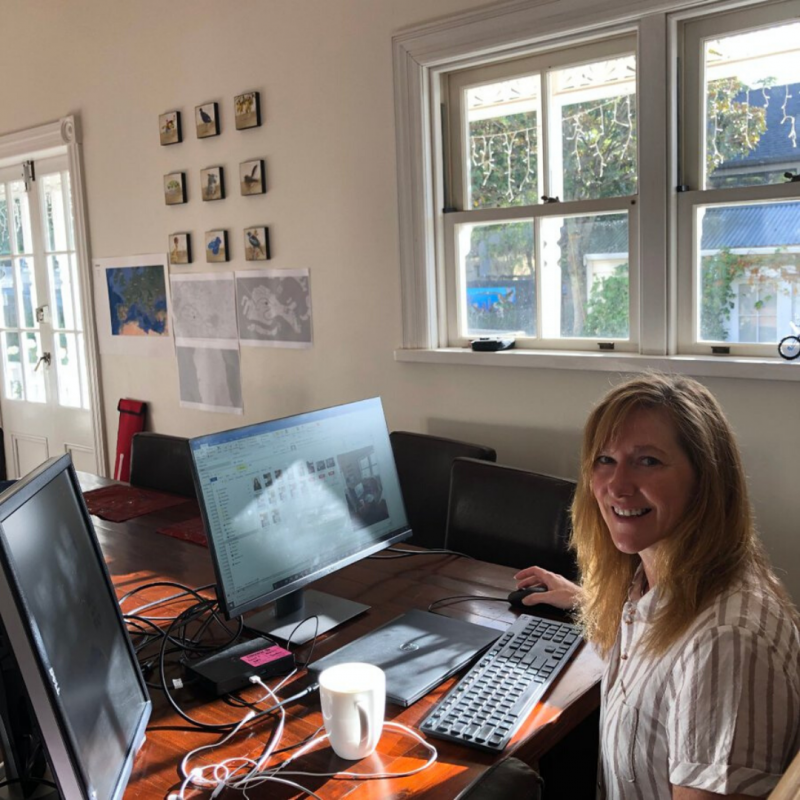 Image of a blonde woman smiling sitting at a desk